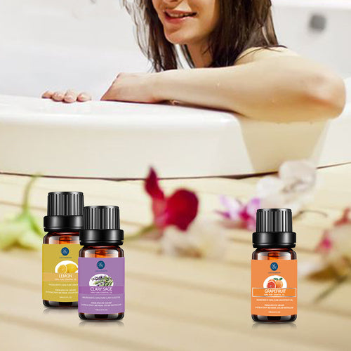 Three essential oil bottles on a surface with a blurred background of a person in a bathtub.
