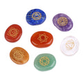 Set of seven chakra stones with gold geometric designs on a white background