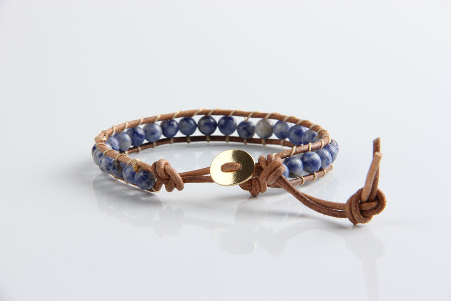 Bracelet with blue beads and a gold button on a white background