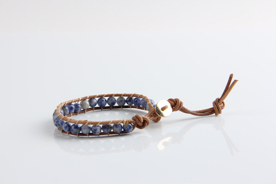 Bracelet with blue beads and brown leather strap on a white background