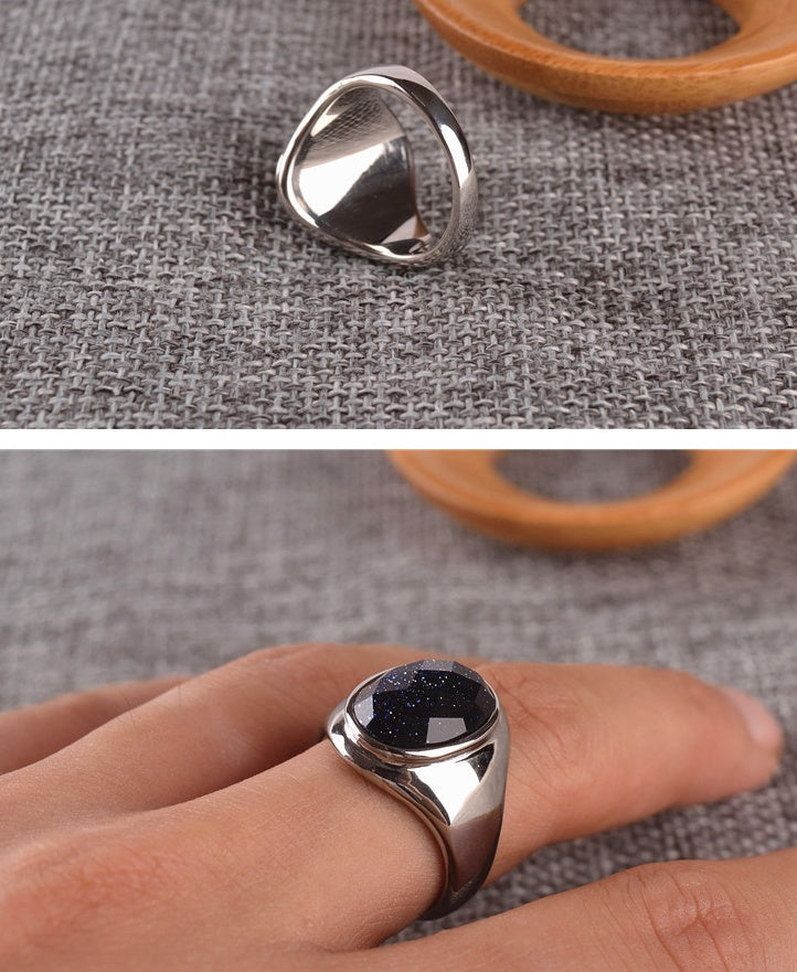Silver ring with a dark stone on a textured fabric background