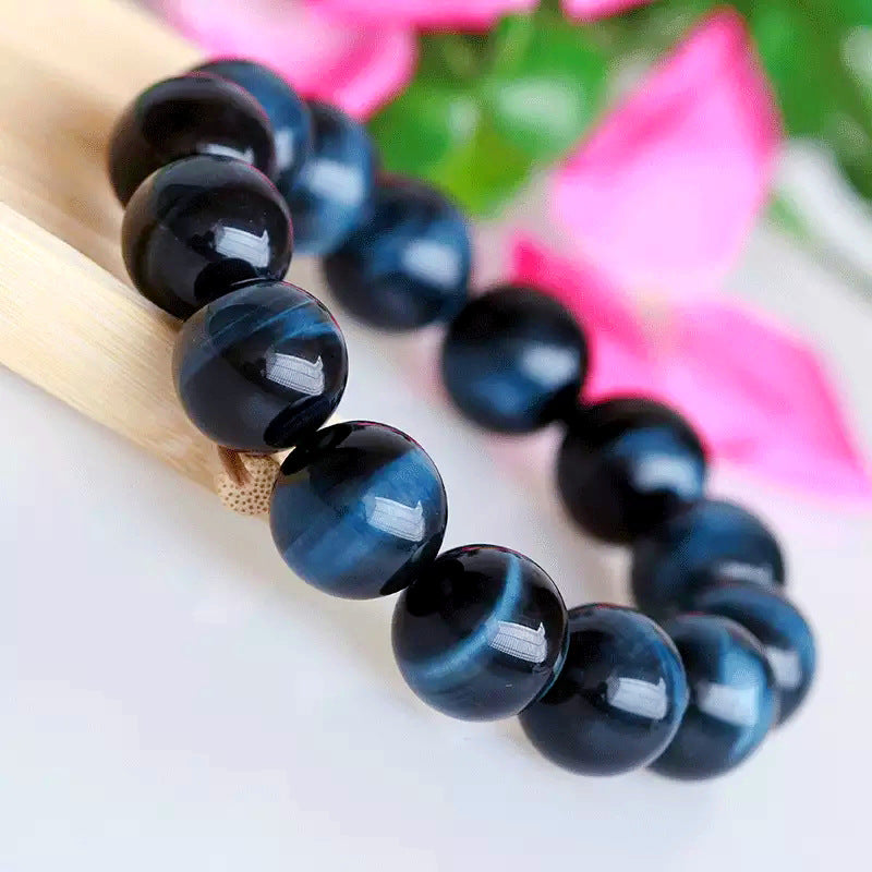 Blue beaded bracelet on a wooden stick with a blurred floral background
