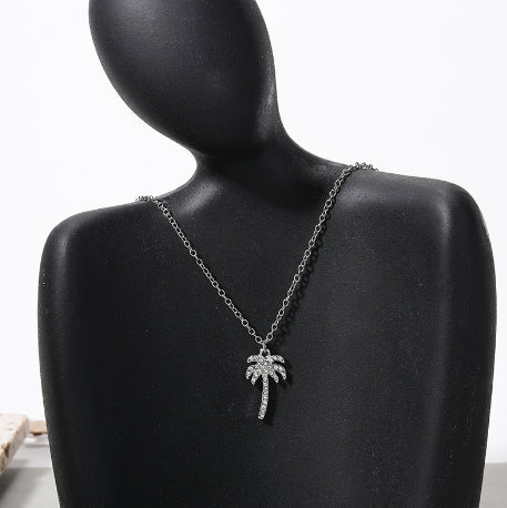 Necklace with a palm tree pendant on a black mannequin bust.