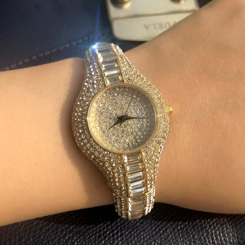 Gold and silver watch with gemstones on a wrist against a dark background
