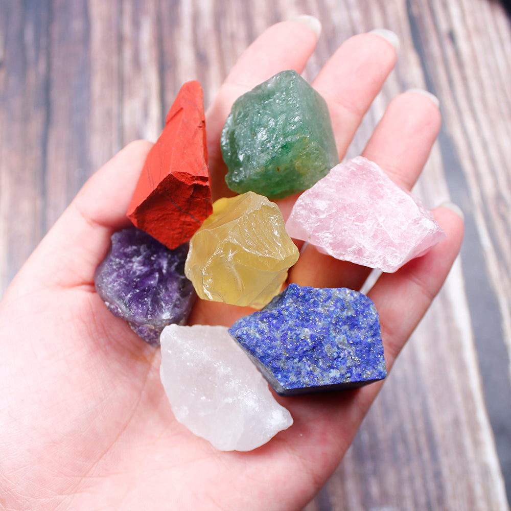 Hand holding a collection of colorful crystals on a wooden surface