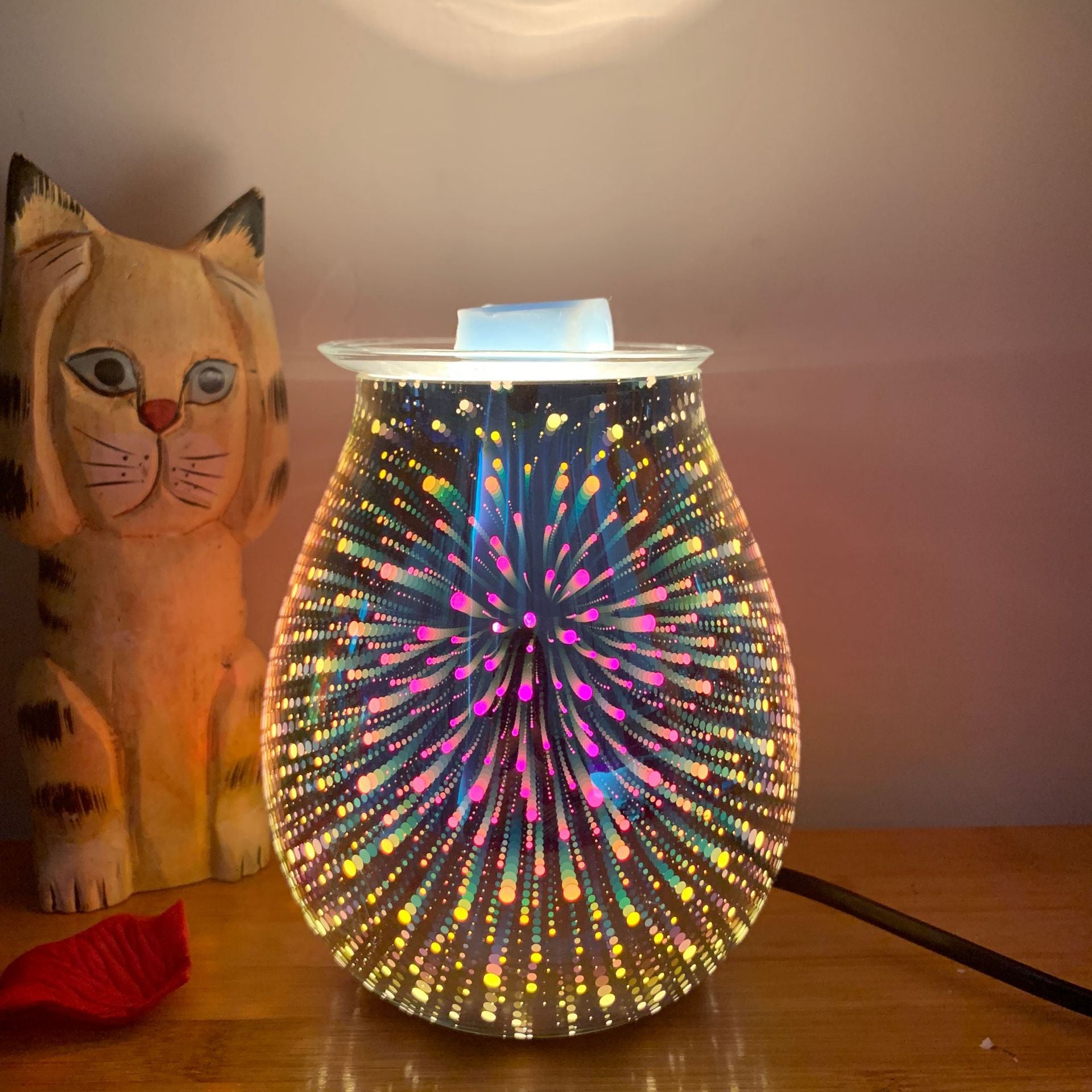 Colorful diffuser lamp on a wooden surface with a cat figurine in the background