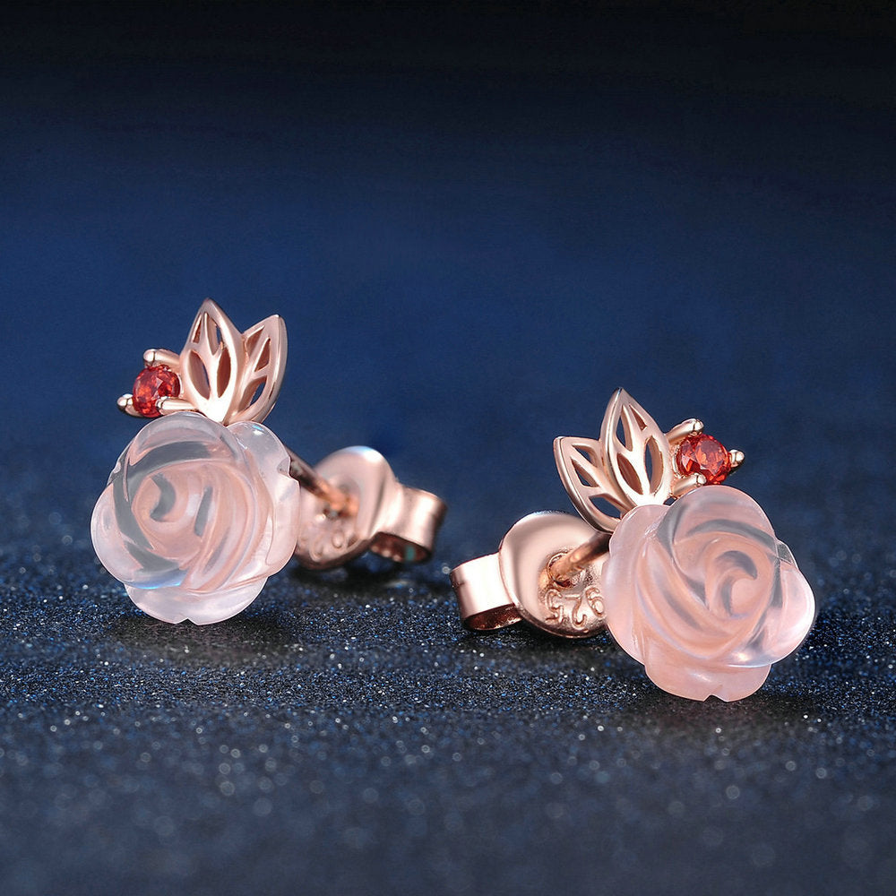 Pair of rose gold earrings with pink gemstones on a dark blue background