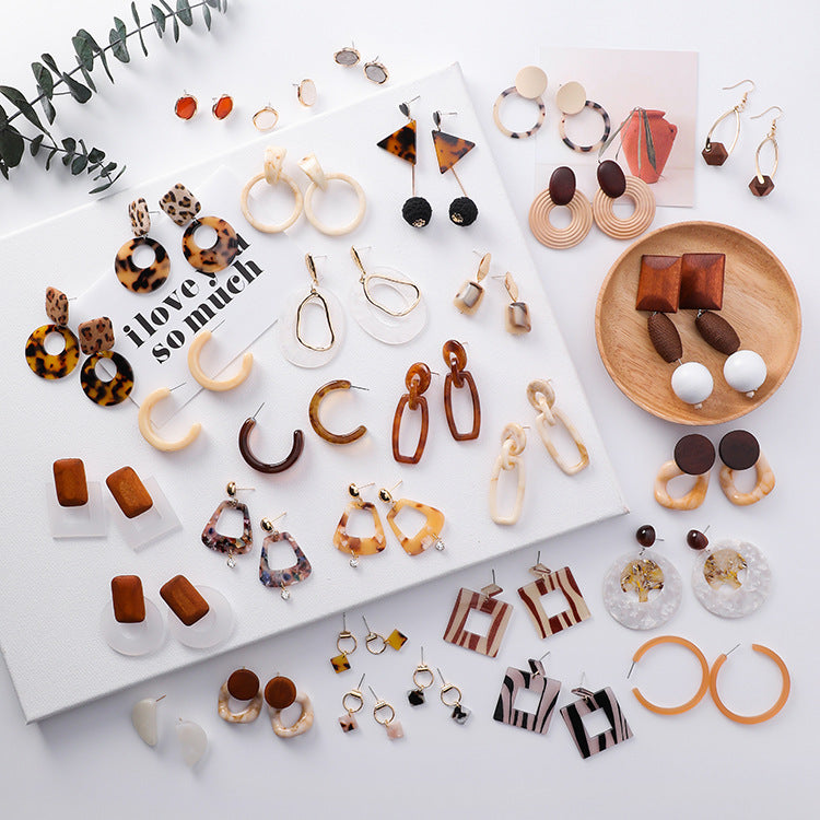 Assorted earrings displayed on a white surface with a magazine and decorative elements.
