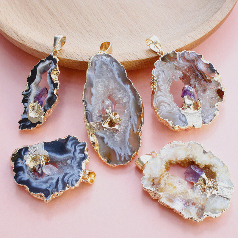 Five agate stone pendants with gold accents on a pink surface.