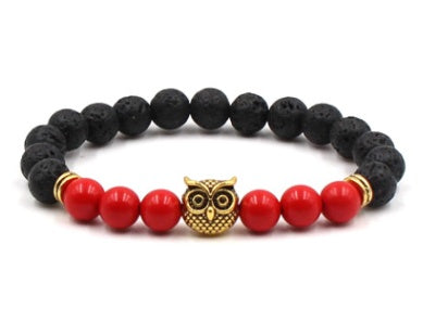 Black lava rock bracelet with red beads and a gold owl charm on a white background
