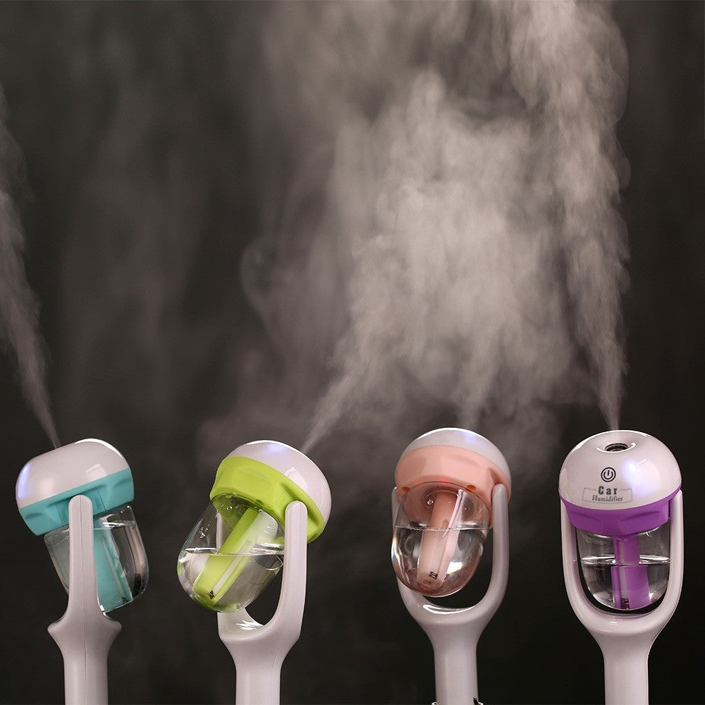 Four colorful humidifier devices emitting steam against a dark background