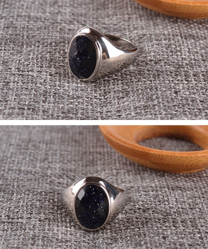 Silver ring with a black stone on a textured fabric background