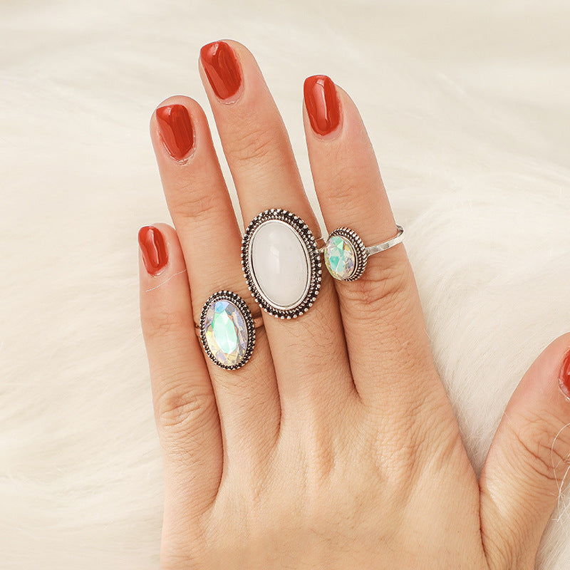 Hand wearing two silver rings with gemstones on a neutral background