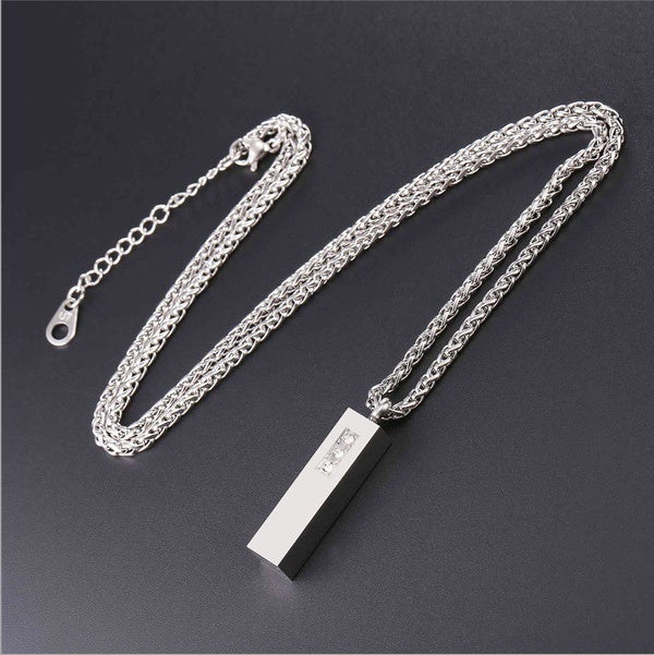Silver chain necklace with a rectangular pendant on a dark background