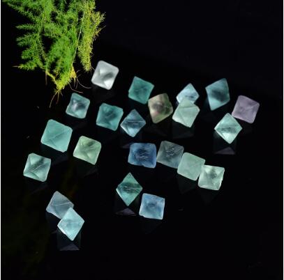 Glowing blue stones on a dark surface with greenery in the corner
