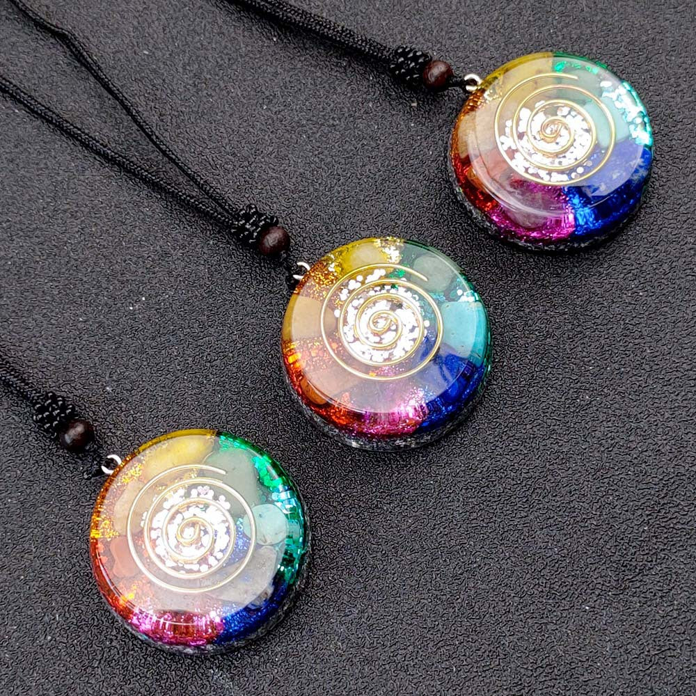 Three colorful circular pendants on black strings against a dark background
