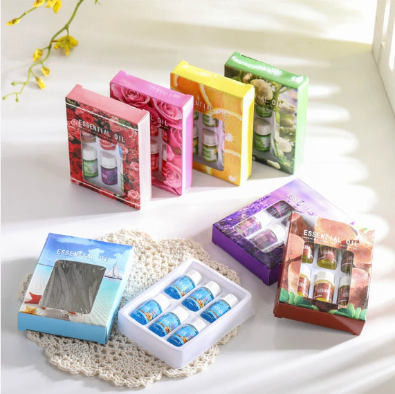 Collection of essential oil sets in various packaging designs on a light surface.