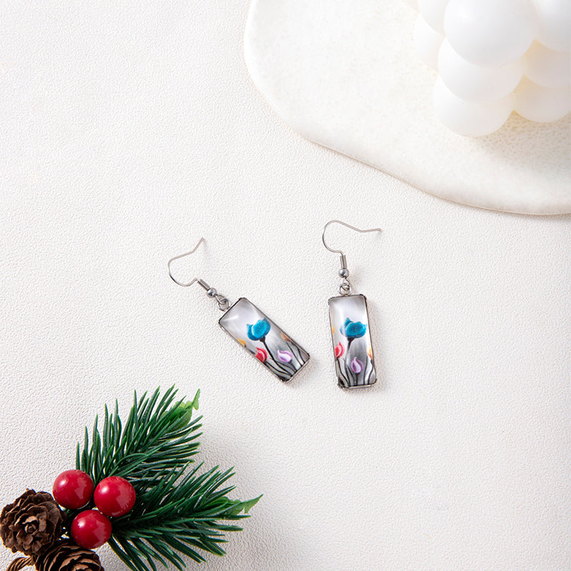 Pair of earrings with floral design on a white surface with decorative elements.