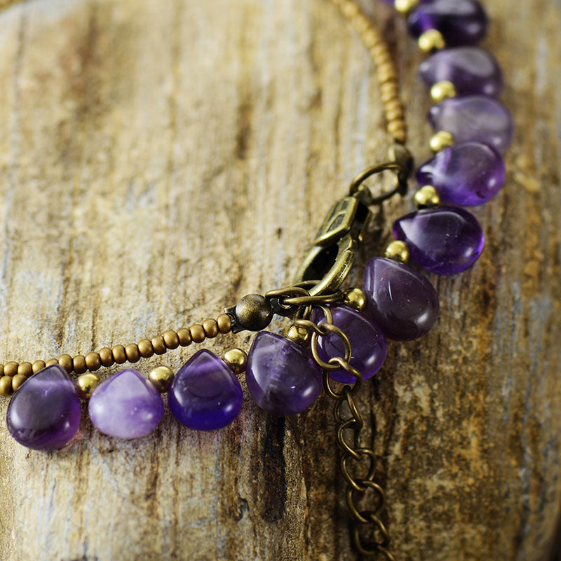 Bracelet with purple beads and gold accents on a wooden surface