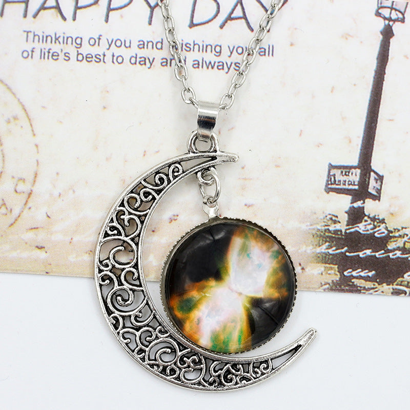 Crescent moon-shaped pendant with a colorful central design on a textured card background