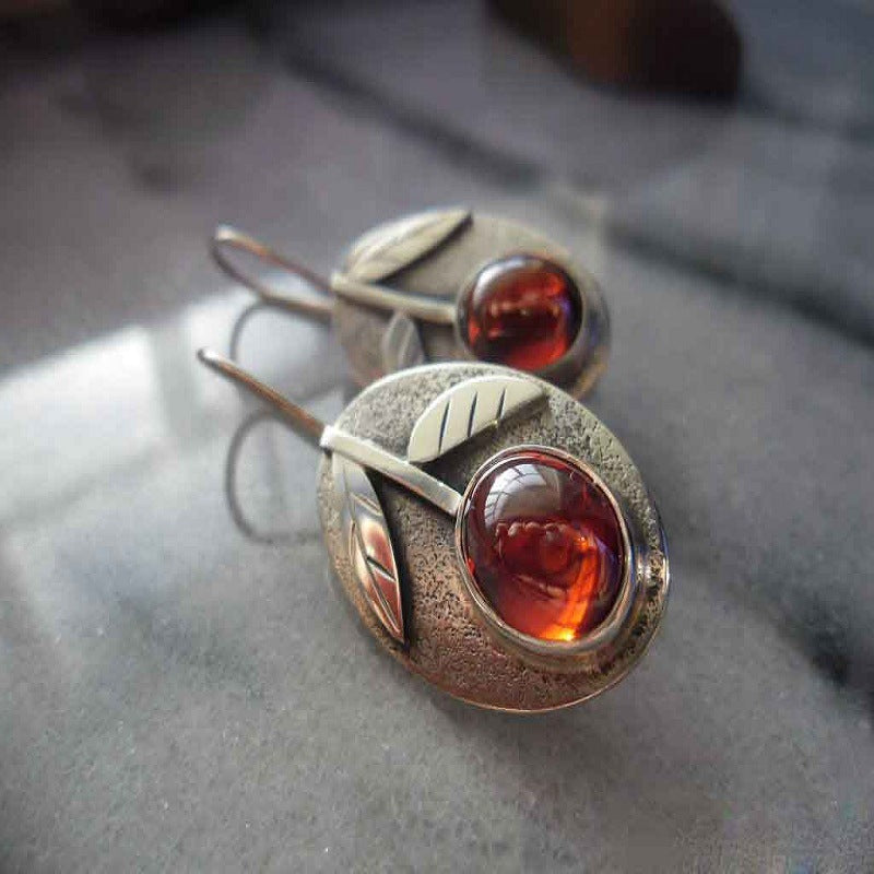 Silver earrings with amber stones on a textured surface