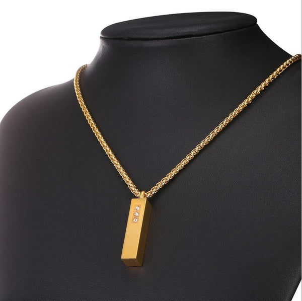 Gold necklace with a rectangular pendant on a black mannequin