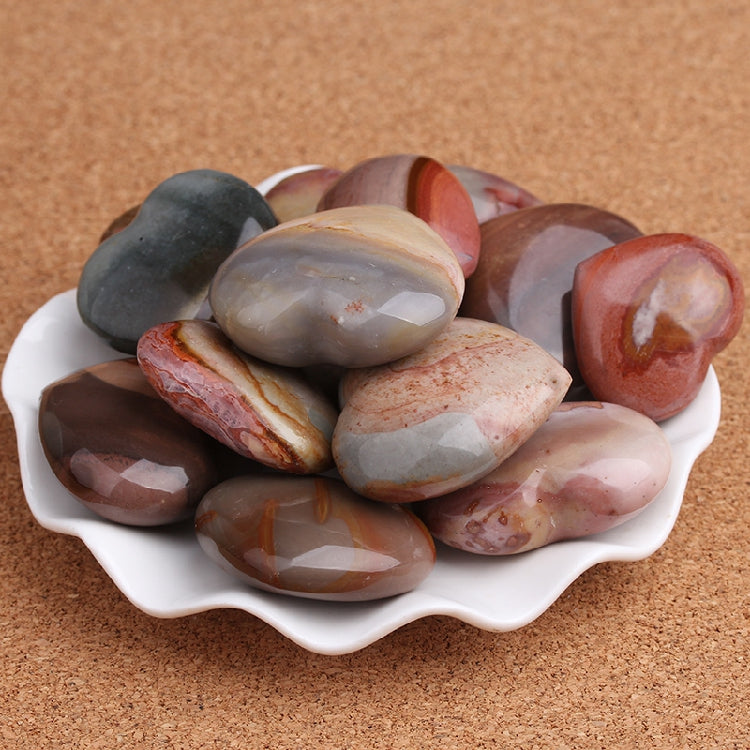 Assorted polished stones in a white bowl on a brown surface