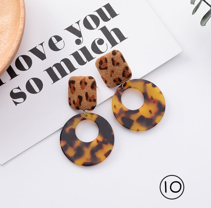 Leopard print earrings on a magazine with text in the background