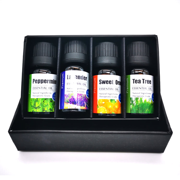 Set of four essential oil bottles in a black display case on a white background
