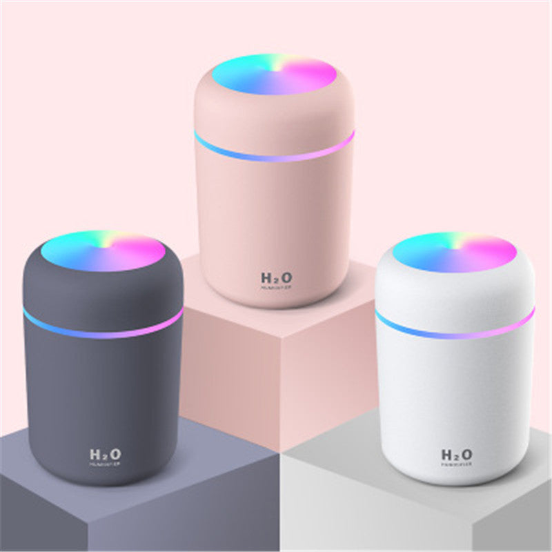 Three cylindrical humidifiers with colorful LED lights on a geometric patterned background