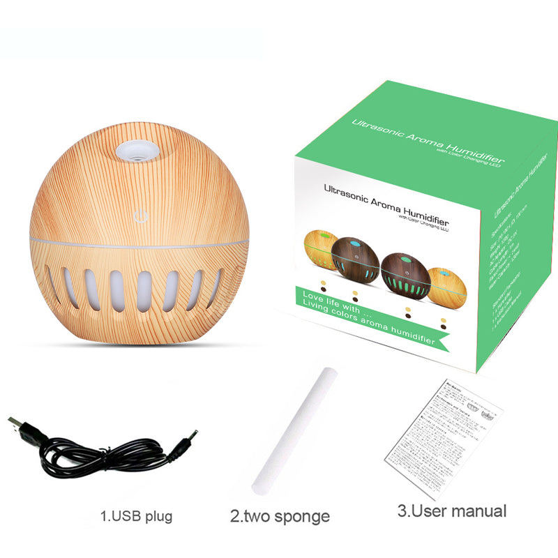 Wooden ultrasonic aroma humidifier with packaging, USB plug, sponges, and user manual on a white background.
