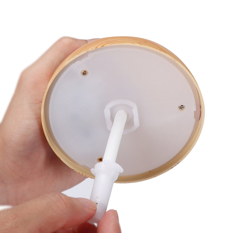 Hand holding a wooden container with a white straw-like object inside on a white background