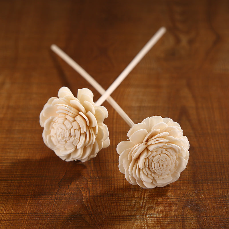Two beige flower-shaped objects on sticks against a wooden background