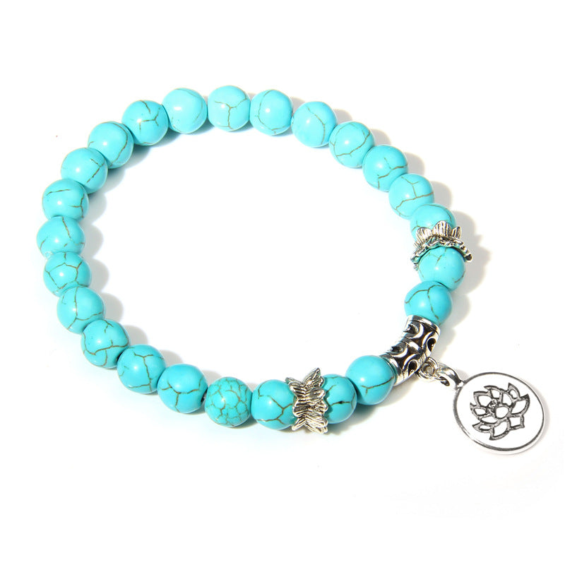 Turquoise beaded bracelet with silver charms on a white background