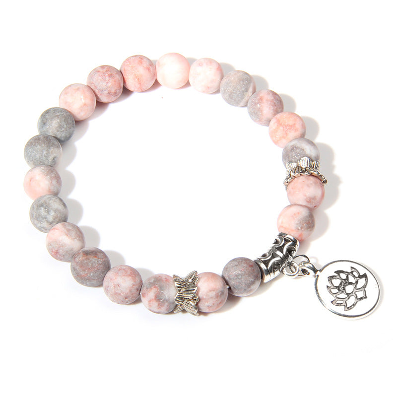 Bracelet with pink and gray beads and a silver charm on a white background