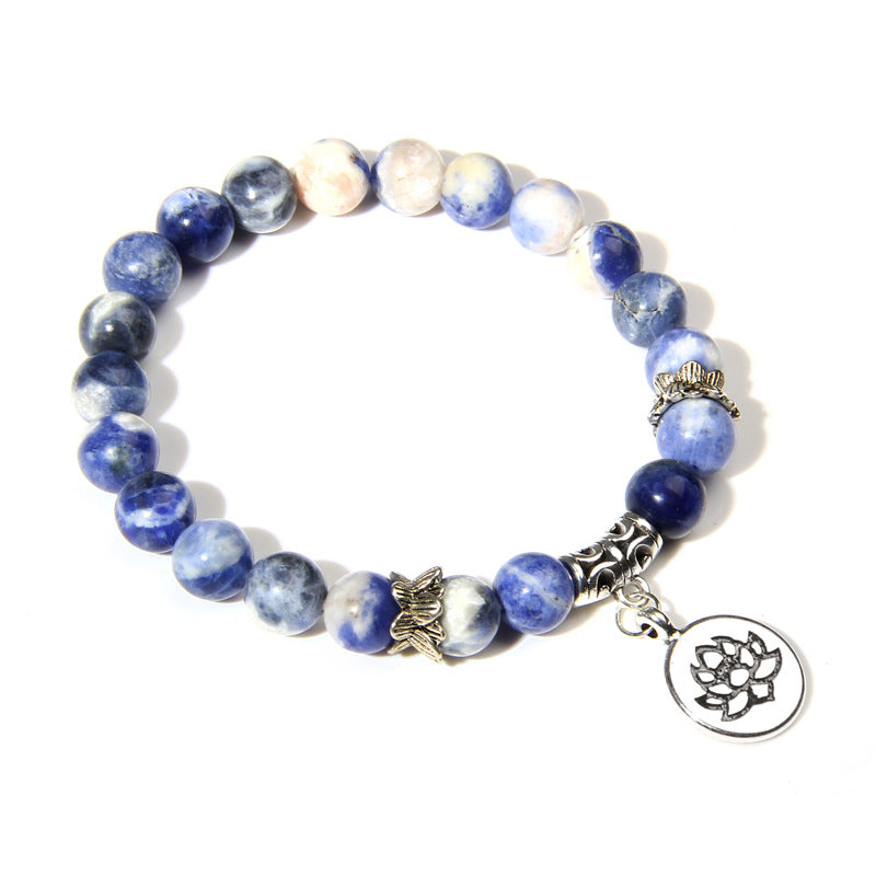 Blue beaded bracelet with a silver lotus charm on a white background