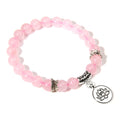 Pink beaded bracelet with silver charms on a white background