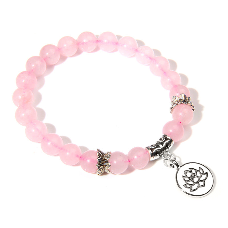 Pink beaded bracelet with silver charms on a white background