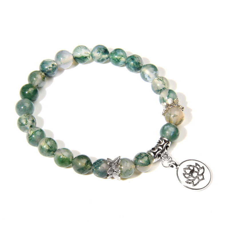 Green beaded bracelet with silver charms on a white background