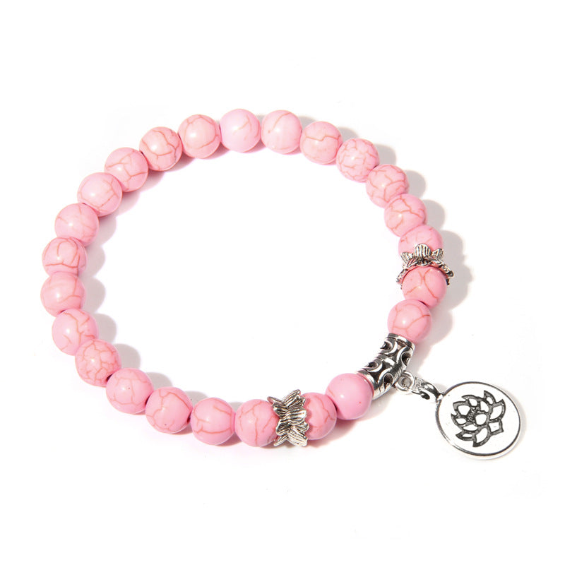 Pink beaded bracelet with silver charms on a white background