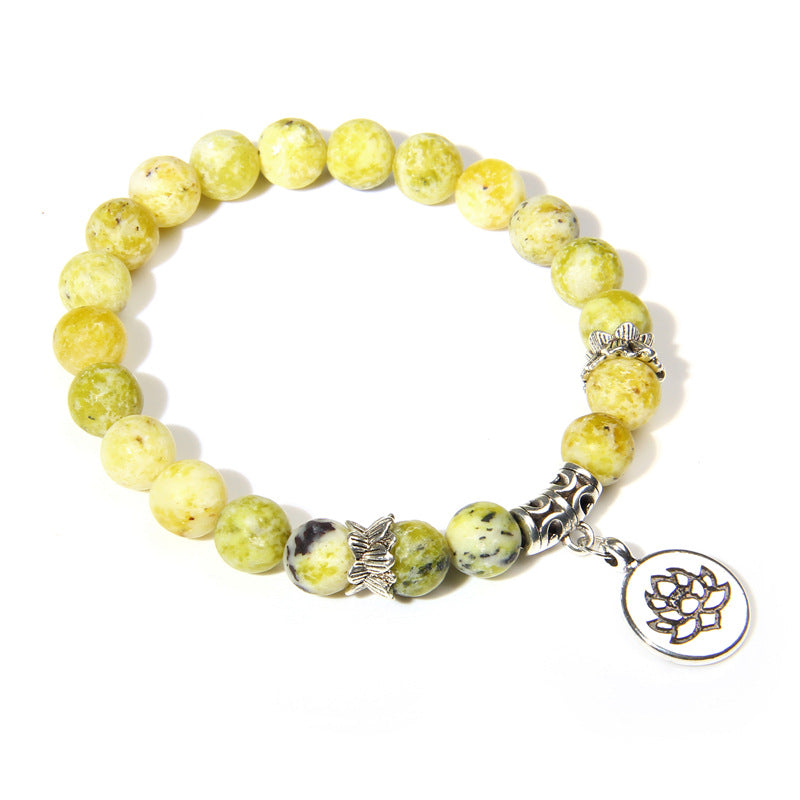 Yellow beaded bracelet with silver lotus charm on a white background