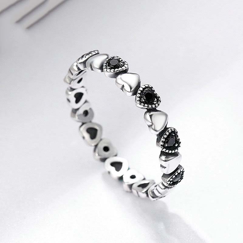 Silver ring with black gemstones on a white background