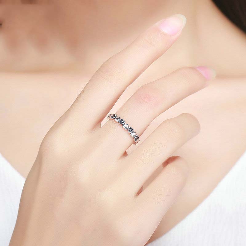 Silver ring with blue gemstones on a hand against a neutral background