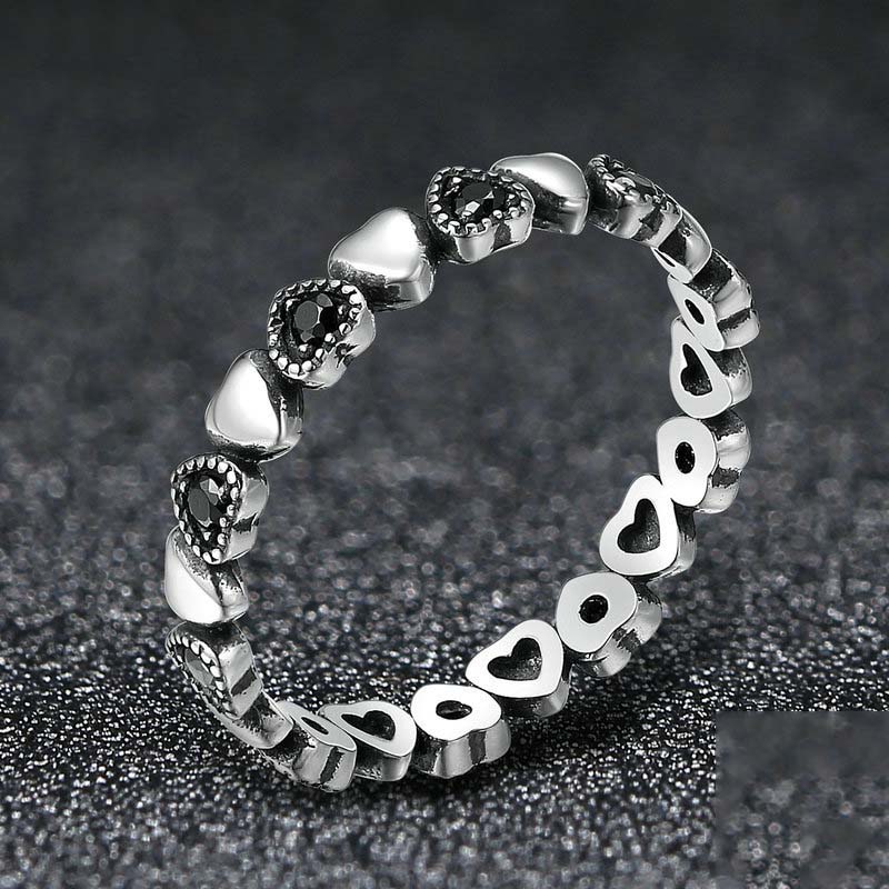Silver ring with heart designs on a dark textured background