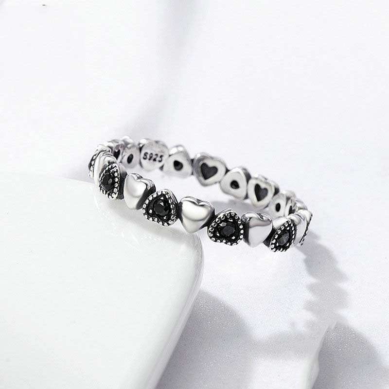 Silver bracelet with heart and black stone details on a white background