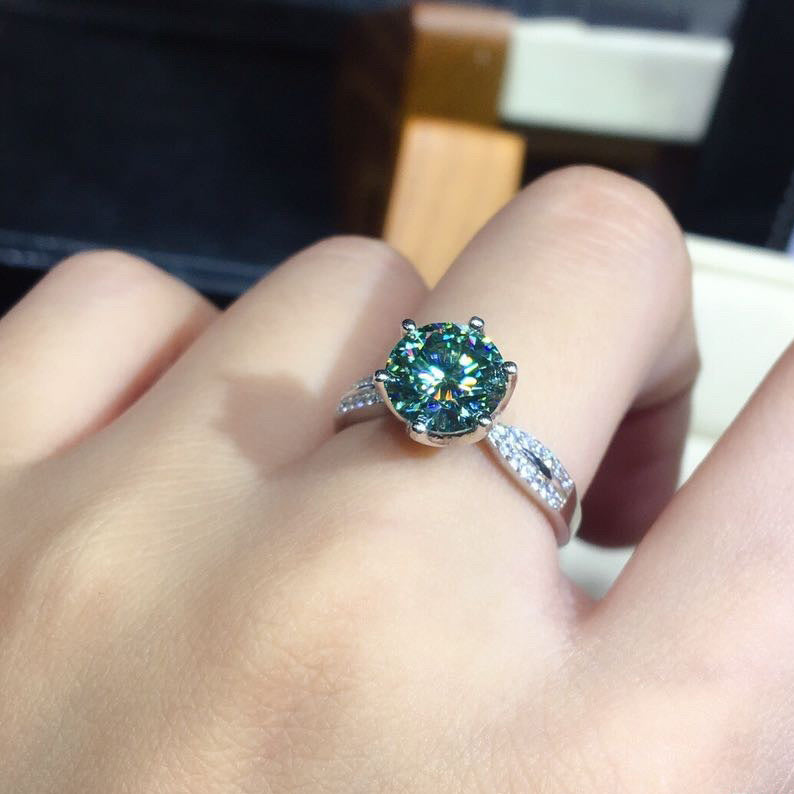 Ring with a green gemstone on a finger, with a blurred background