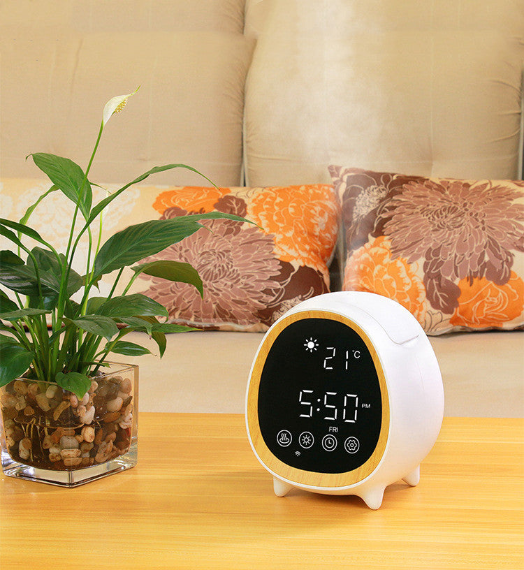 Digital clock on a wooden surface with a plant and decorative pillows in the background