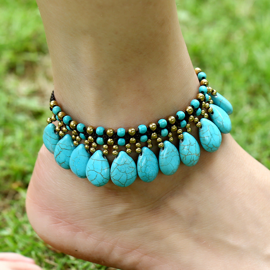 Turquoise beaded anklet on a foot with grass in the background