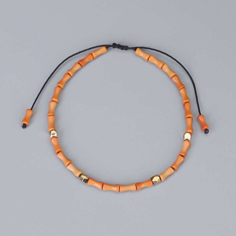 Necklace with orange beads and black cord on a gray background
