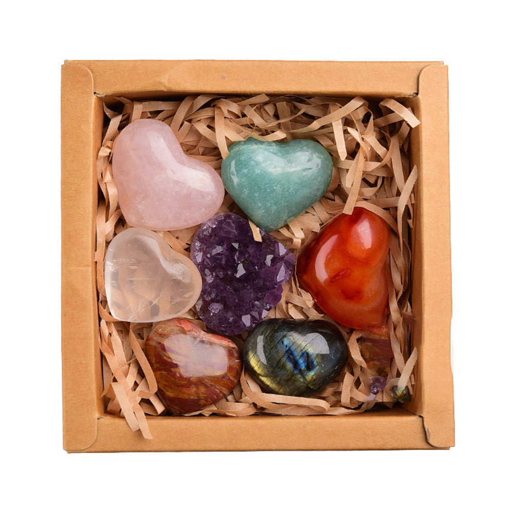 Box of heart-shaped colorful stones on a white background